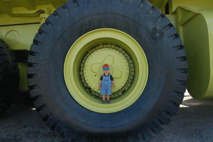 Ребенок стоит на ободе гиганского колеса