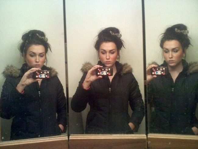 Привлекательные  девушки фотографируют свое отражение в зеркале